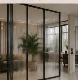 ١٩ تصميم فواصل وقواطع — قاطع زجاجي بإطار نحيف: زجاج بإطارات نحيفة يفصل المساحات مع رؤية كاملة.